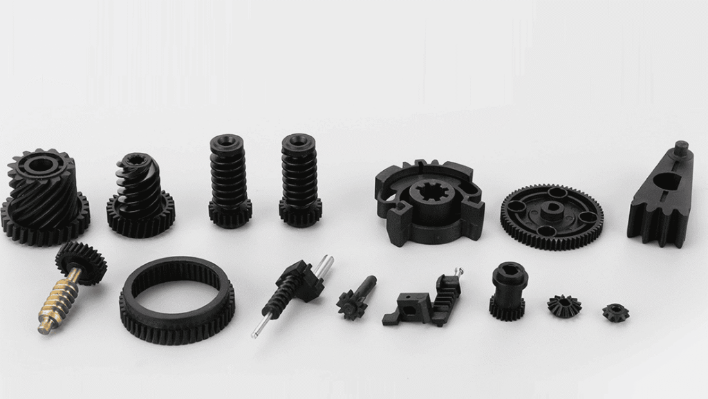 Diverse plastic gear components including worm gears, helical gears, bevel gears and ring gears in black engineering plastic