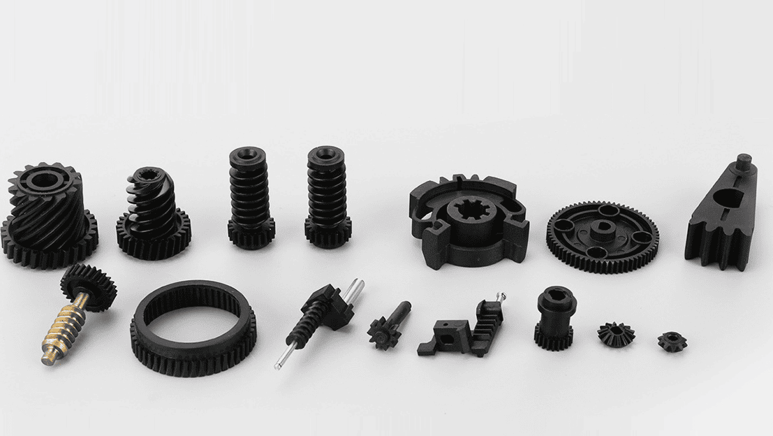 Diverse plastic gear components including worm gears, helical gears, bevel gears and ring gears in black engineering plastic